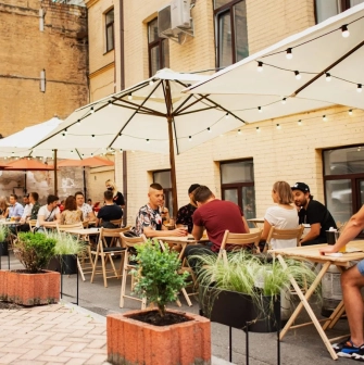 Punkraft - relaxed street terrace with simple wooden tables and strung lights