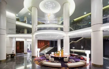 The luxurious lobby of the Hilton Kyiv Hotel with columns, a round seating area and a modern chandelier