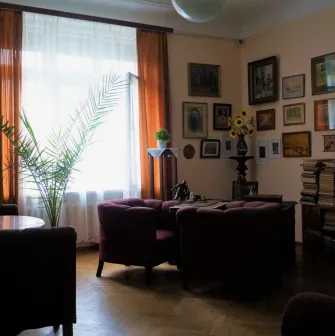 Muzei Tychyny in Kyiv - atmospheric living room featuring a grand piano, velvet armchairs, and a wall gallery of framed paintings