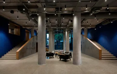 Teatr na Podoli in Kyiv - minimalist theater lobby interior with raw concrete columns, blue walls, and modern lounge seating