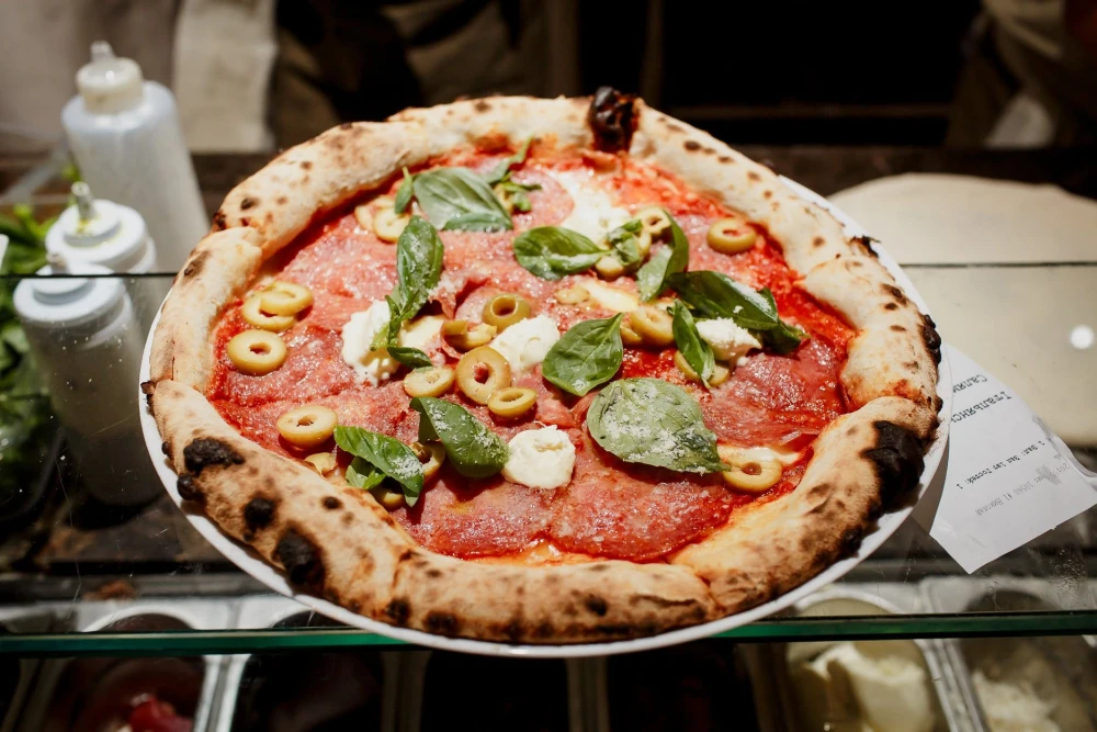 Pizza with salami, olives, and greens at Tisto, Syr ta titka Bella