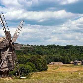 Panorama of the Pies Museum with wooden mills on a green field in Kyiv