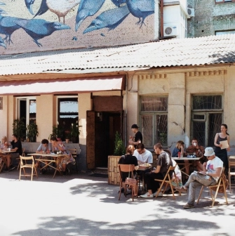 Kashtan - sunny outdoor patio with people dining under a mural of birds