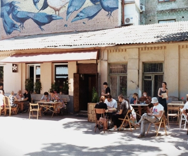 Kashtan - sunny outdoor patio with people dining under a mural of birds