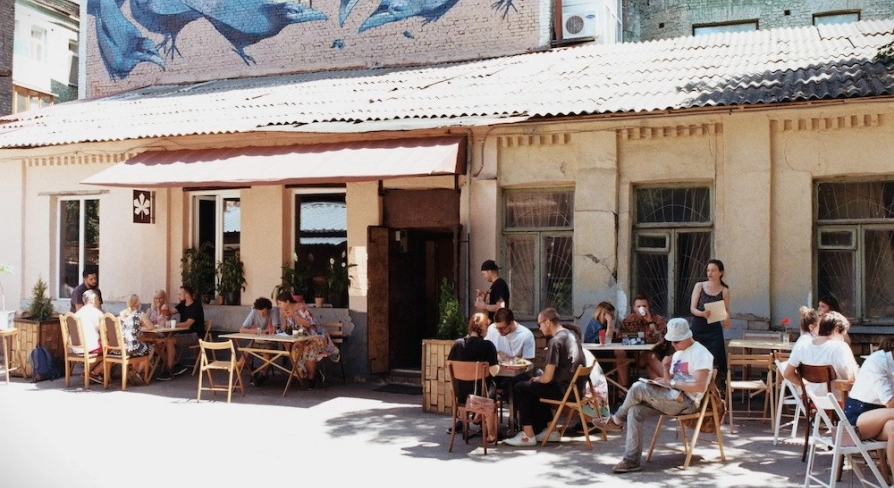 Kashtan - sunny outdoor patio with people dining under a mural of birds