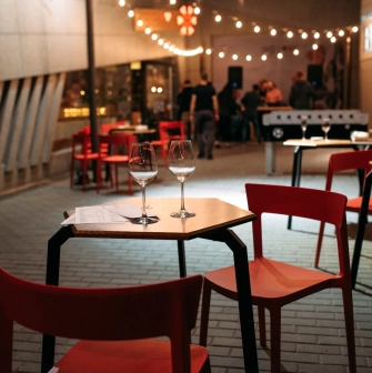 One Love Coffee in Kyiv - evening terrace setting with wine glasses on table and red chairs