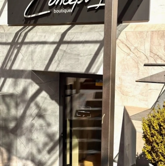 Concept 1 Boutique in Kyiv - entrance to the shop featuring a marble facade and a black sign with the logo above the glass door