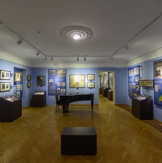 Muzei Ukrainskoi Diaspory in Kyiv - atmospheric blue hall featuring a black grand piano in the center surrounded by framed art and display cases