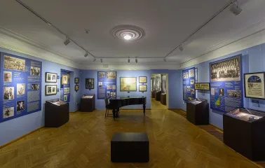 Muzei Ukrainskoi Diaspory in Kyiv - atmospheric blue hall featuring a black grand piano in the center surrounded by framed art and display cases