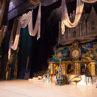 National Opera of Ukraine in Kyiv - atmospheric stage setting for a performance featuring large elegant drapes, a clock, and a festive Christmas tree