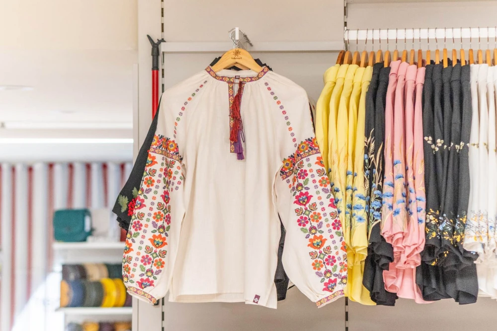 A white vyshyvanka with colorful patterns on a hanger in a store.