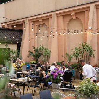 Restaurant Italiets iz Beiruta - people dining outdoors on a patio decorated with plants and string lights