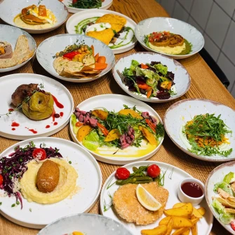 Trishky Bilshe – table with assorted dishes and colorful salads on white plates