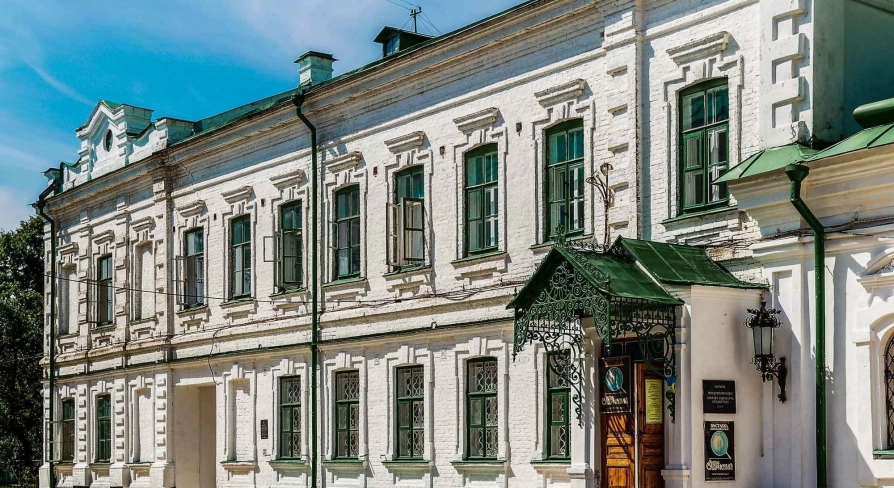 Mykola Syadristy Microminiatures Museum in Kyiv - historic white building with green framed windows and an ornate wrought-iron entrance canopy located in the Kyiv Pechersk Lavra