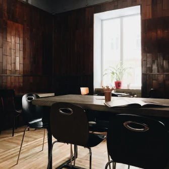 Kashtan - indoor dining area with wooden paneling a large table and sunlight through the window