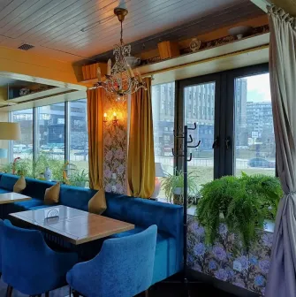 Restaurant Kukhnya Polli - bright and cozy dining room with simple wooden tables and large windows