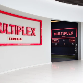 Main entrance to the Multiplex cinema with a red sign and a movie poster