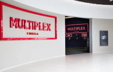 Main entrance to the Multiplex cinema with a red sign and a movie poster